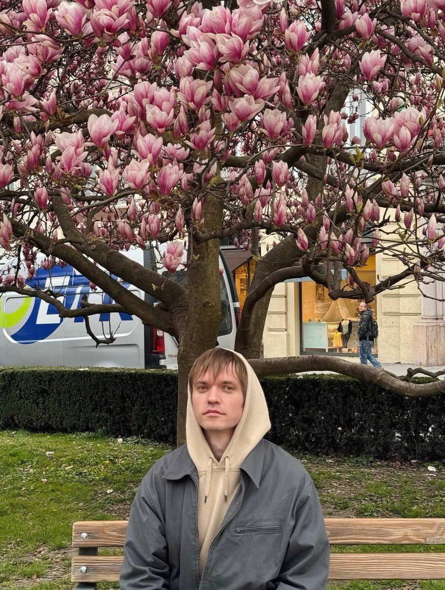 Maksym Zubkov seated beneath a blooming magnolia tree